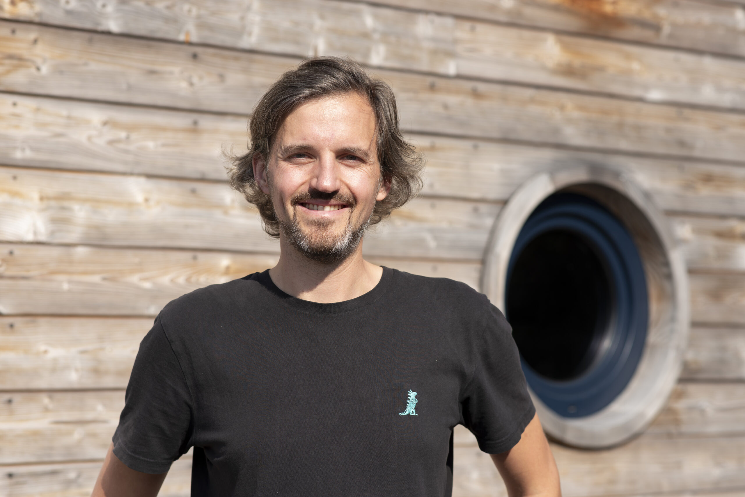 Evan Rost, Geschäftsführer des Hausboot Hafens Hamburg und Betriebsleiter der Grube Werft vor der Holzfassade eines Hausboots.